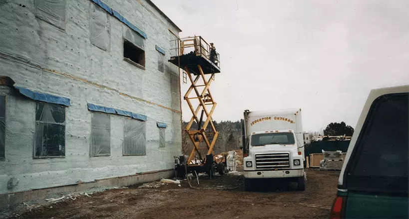 Équipe Isolation Guylmar appliquant la mousse polyuréthane sur un bâtiment commercial avec nacelle élévatrice